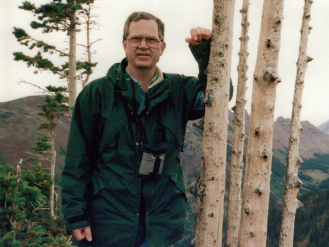 Dr. Richard Johnson outdoors, leaning against a tree and facing camera. 