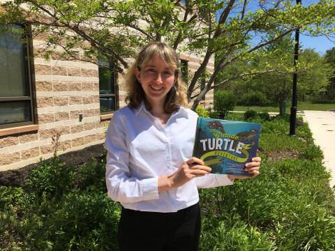 Dr. Helen Bailey poses with the children's book she wrote, The Grande Turtle Adventure.