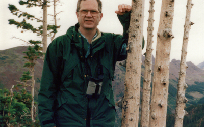 Dr. Richard Johnson outdoors, leaning against a tree and facing camera. 