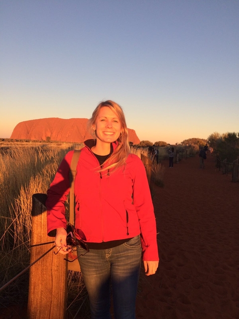 Maggie Triska standing in Australian Outback with Uluru  in the background. 